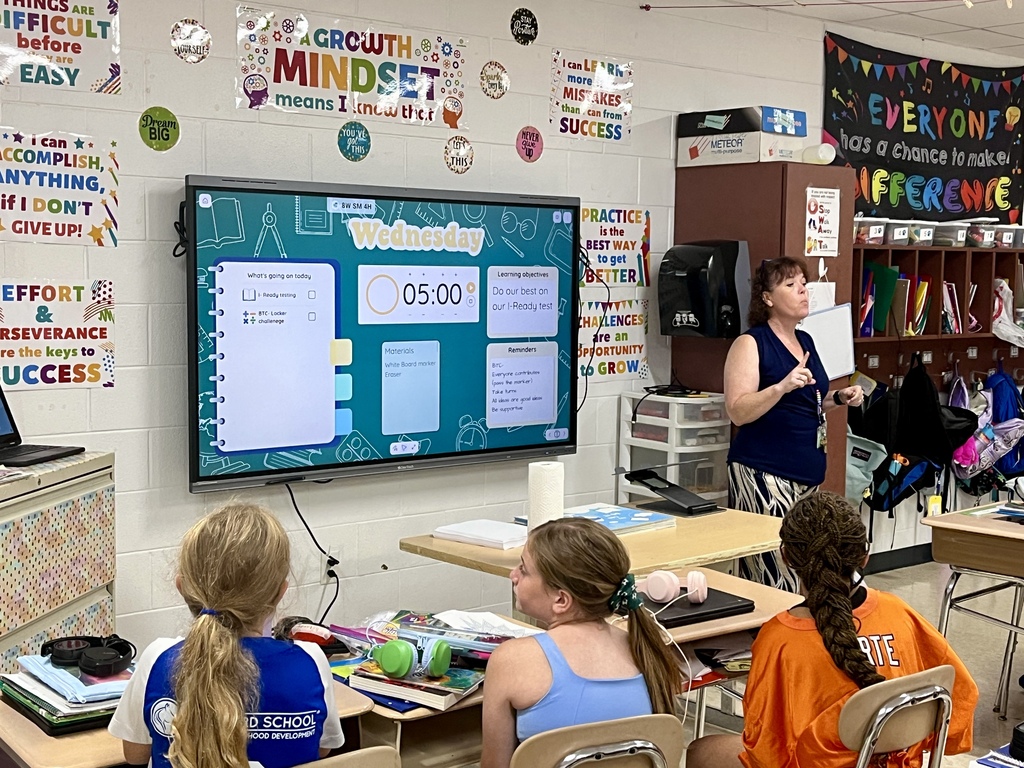 Students work together to solve a complex math problem on the whiteboards around the classroom