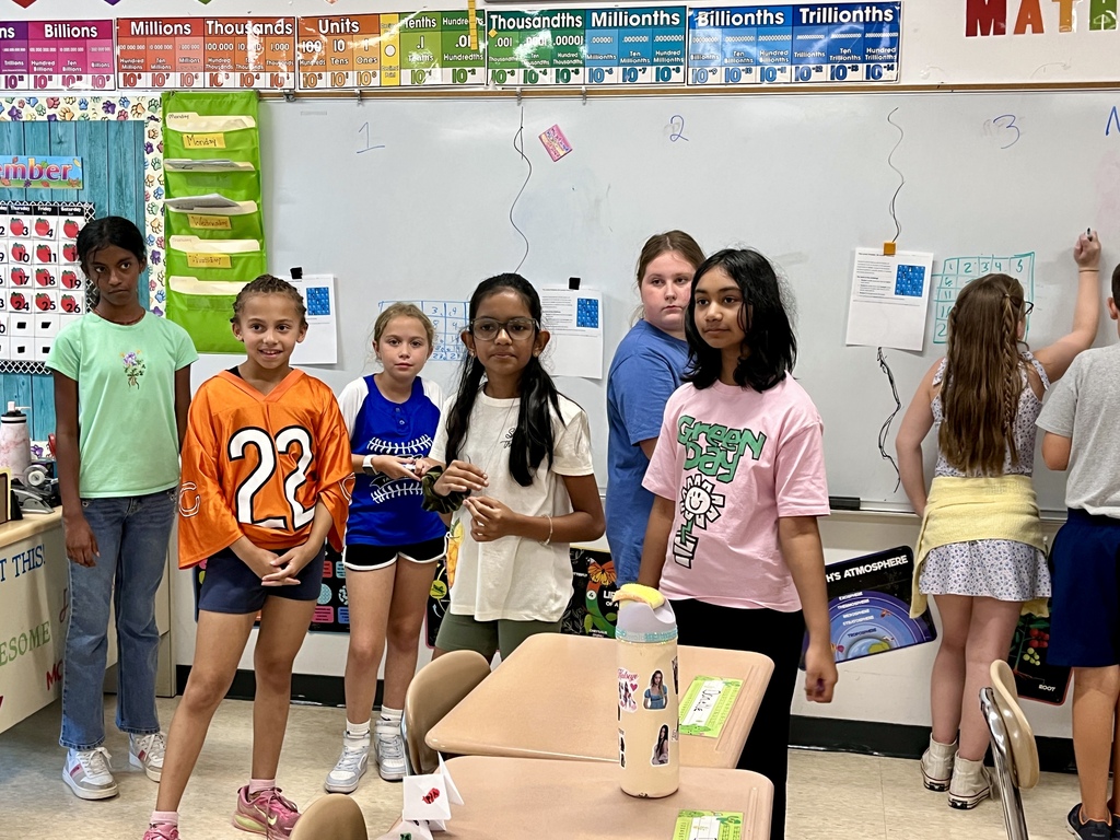 Students work together to solve a complex math problem on the whiteboards around the classroom