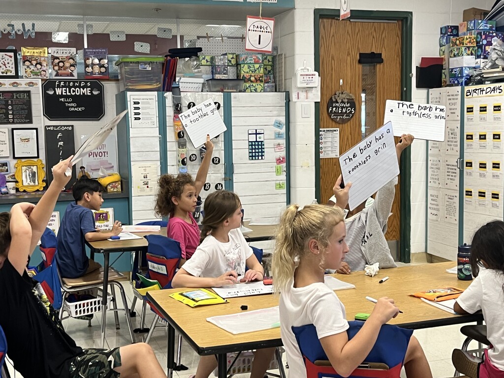 Students show their work on a dry erase board