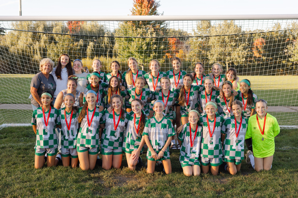 girls soccer team posed in front of soccer net