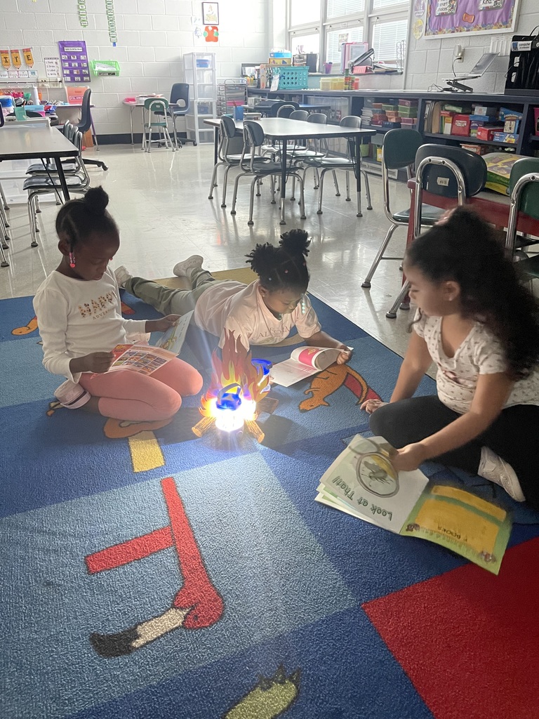 Students on carpet reading around fake campfire