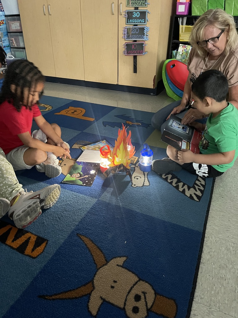 Teacher reading to student with fake campfire