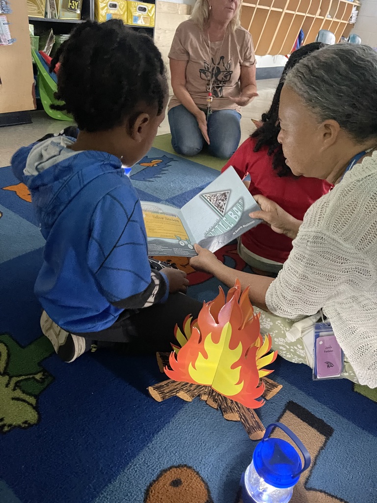 Teacher reading to student with fake campfire