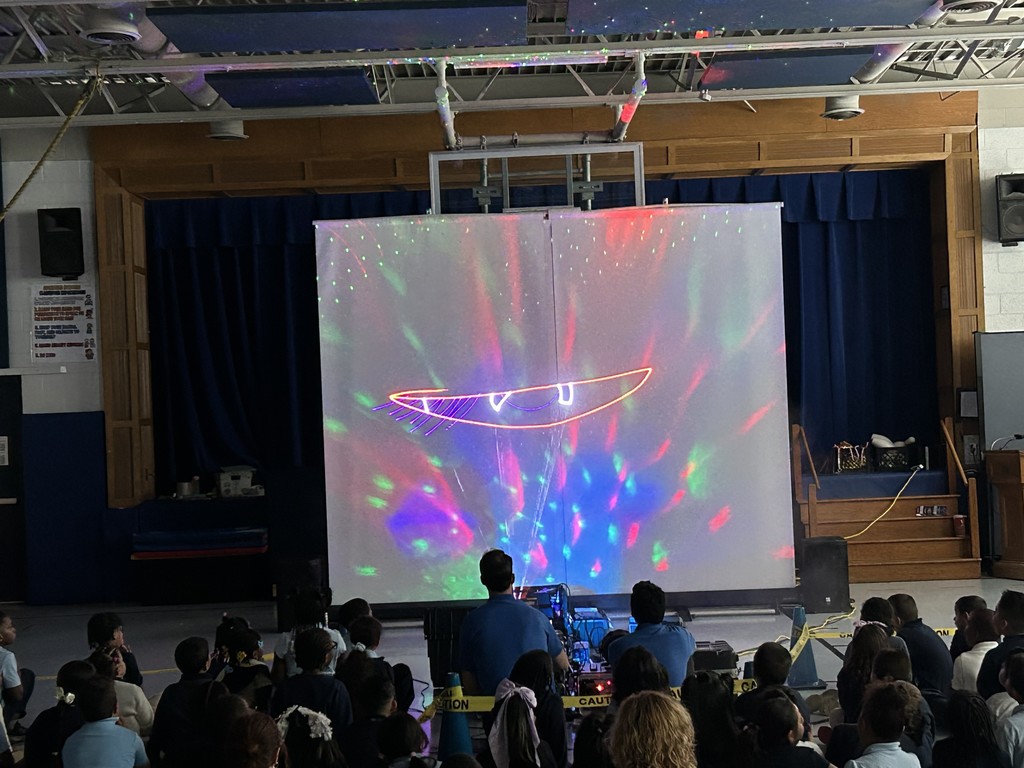 Students on the gym floor with screen with laser show!