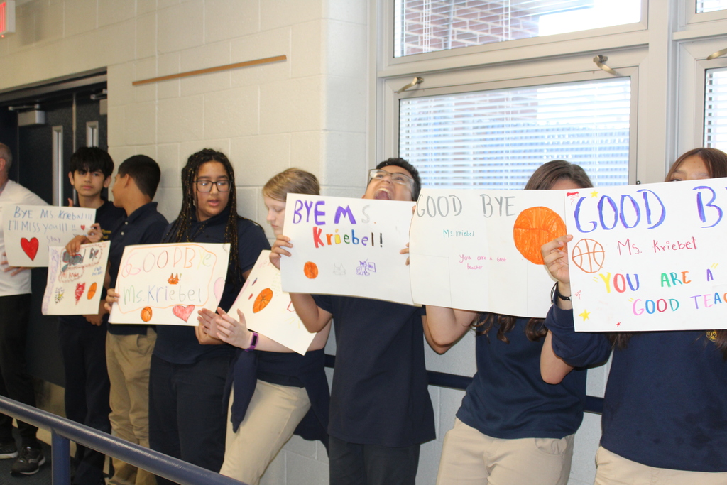 Students holding up good luck retirement signs in hallway