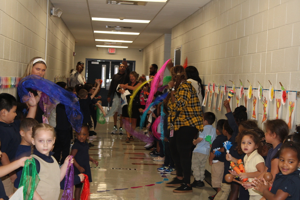 small students holding up clappers and retirement signs in hallway