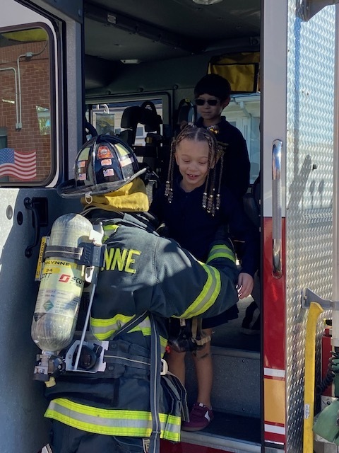 fireman helping a student down from the fire truck