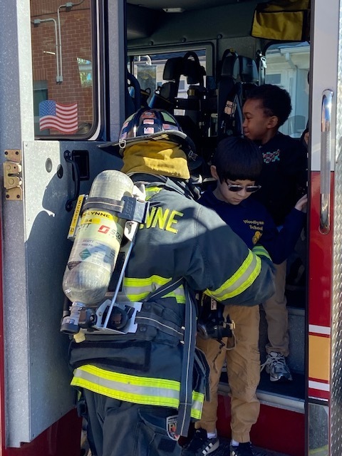 fireman helping a student down from the fire truck