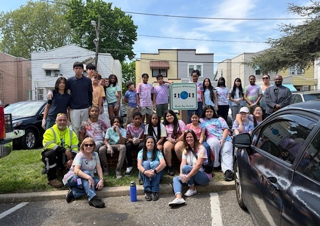 7th grade in front of the sign for the community garden and all the voluteers