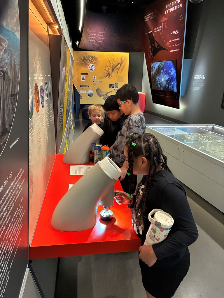 students in a musuem loooking through microscope