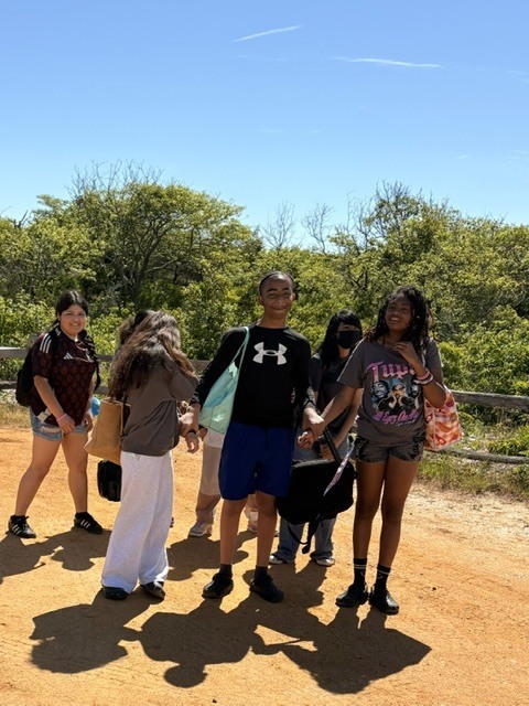 students dressed in beach attire walking down a path to the shore