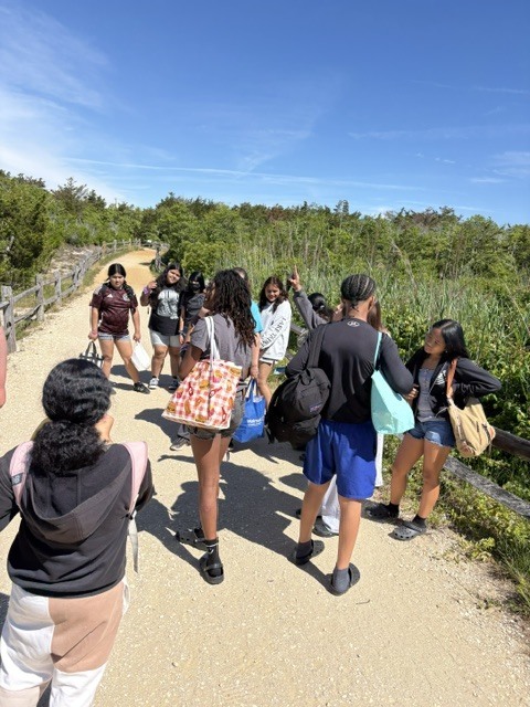 students dressed in beach attire walking down a path to the shore