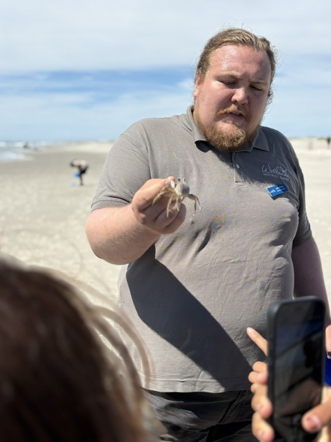 Wetlands inst instructor on the beach with students holding a crab