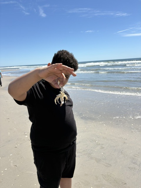 student holding a crap on the beach