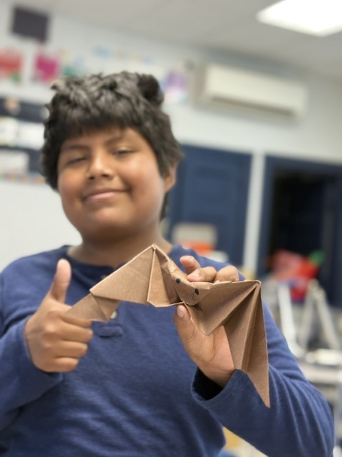 Student holding an oragami bat