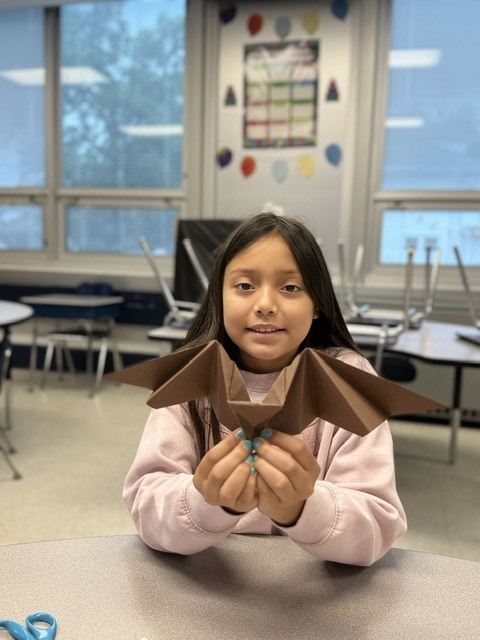 student holding an oragami bat