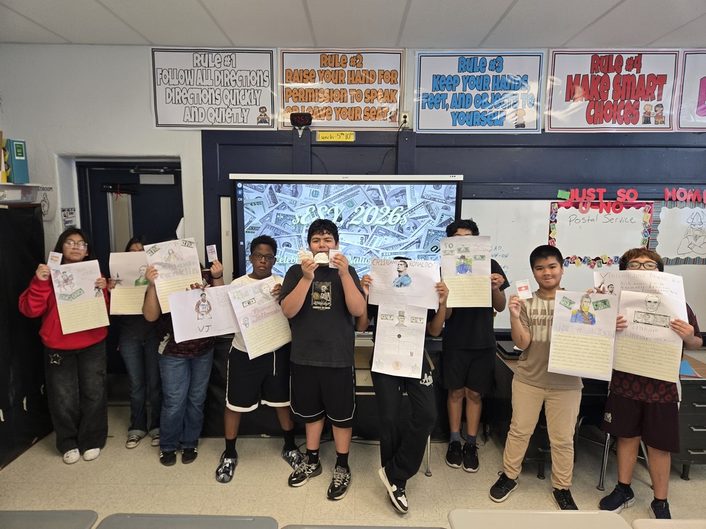 Middle school students holding up their projects they worked on