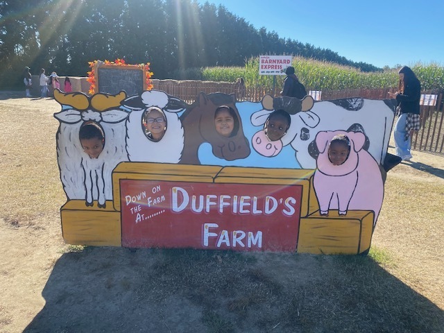 students with their heads through a sign for duffields farm