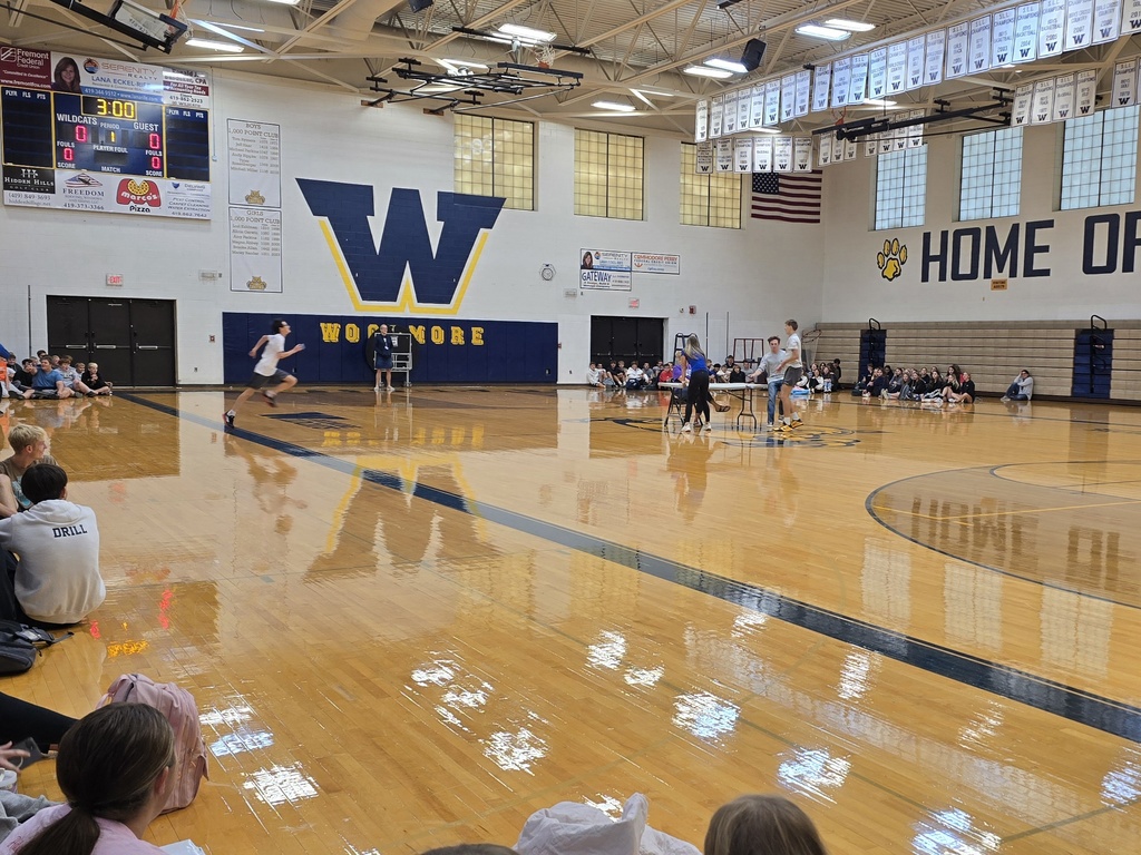 Students running items out to Mrs. Valasek in the center of the gym for the Scavenger Hunt