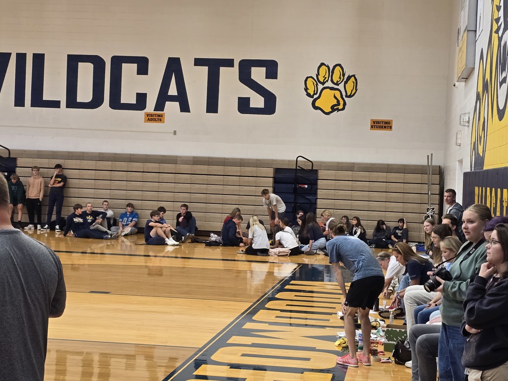Juniors waiting in their corner and staff waiting under the basketball hoop in the gym to see what is needed next in the Scavenger Hunt