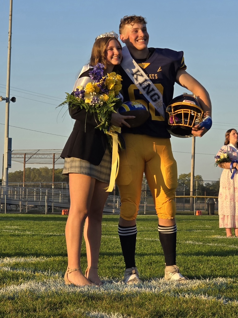King and Queen posing for pictures on the football field