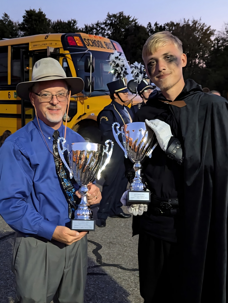 Mr. Emerine and a student show off two of their trophies from the night.