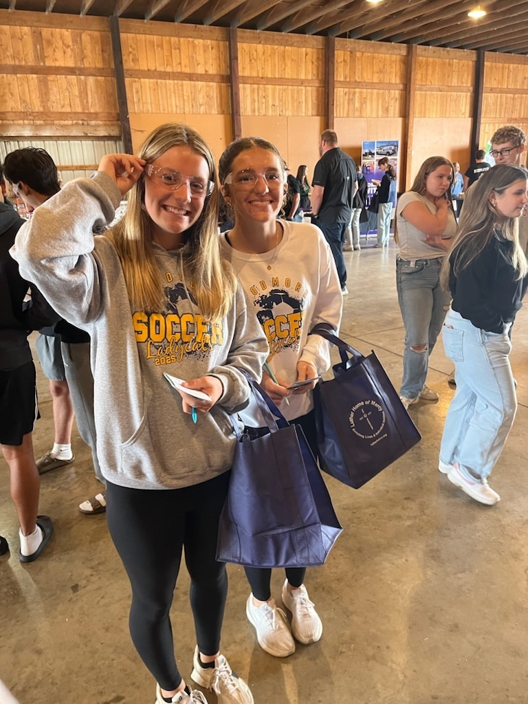 Two students showing off their safety glasses while standing in the Career Showcase.