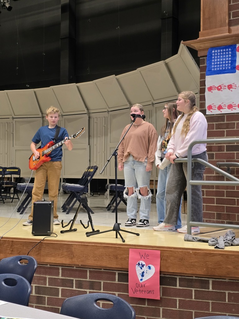 Three eighth grade students sing the National Anthem while Rhett Baker accompanies them on the guitar.