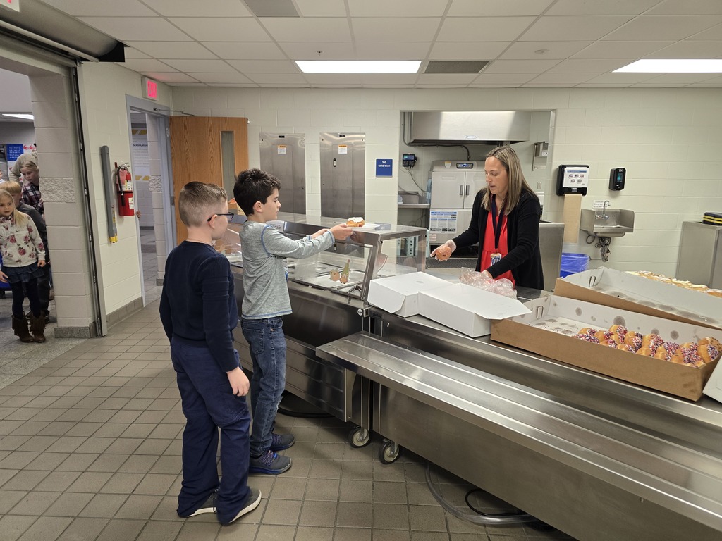 Two fourth grade students get plates from Mrs. Clouse in the kitchen to take them to the Veterans and families.