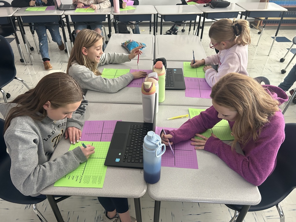 Four sixth grade students play coordinate grid battleship in pairs by sitting across from each other.