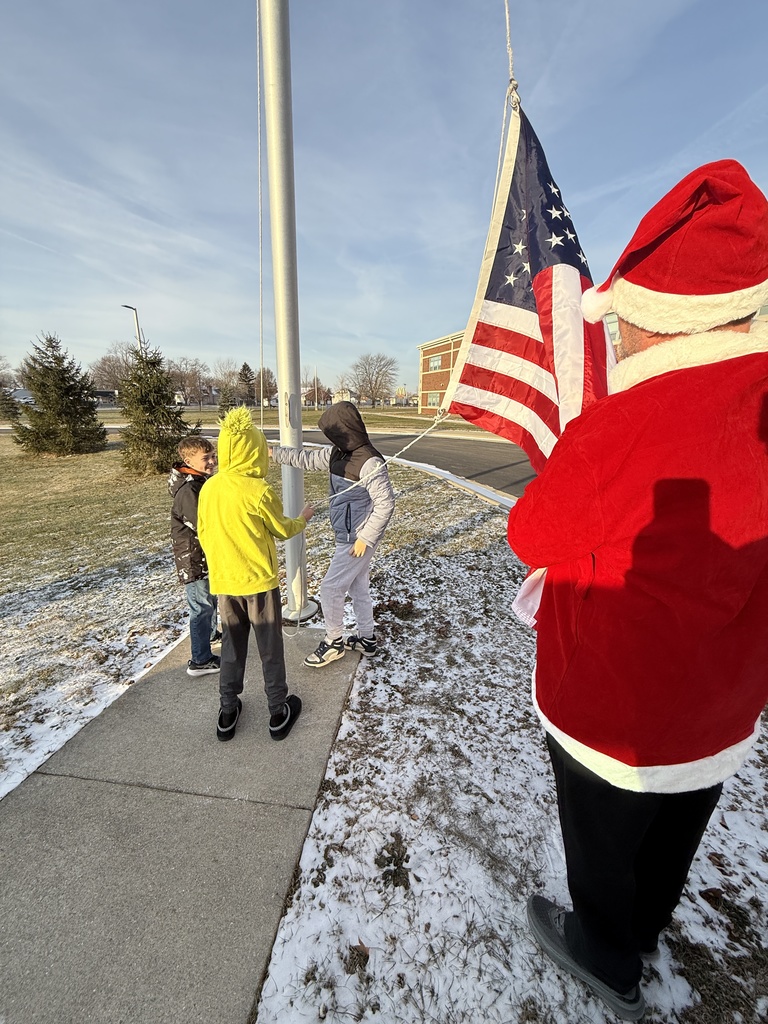The three students get the rope pulley going to hoist the flag while Mr. Barrett holds the end to ensure the flag doesn't touch the ground.