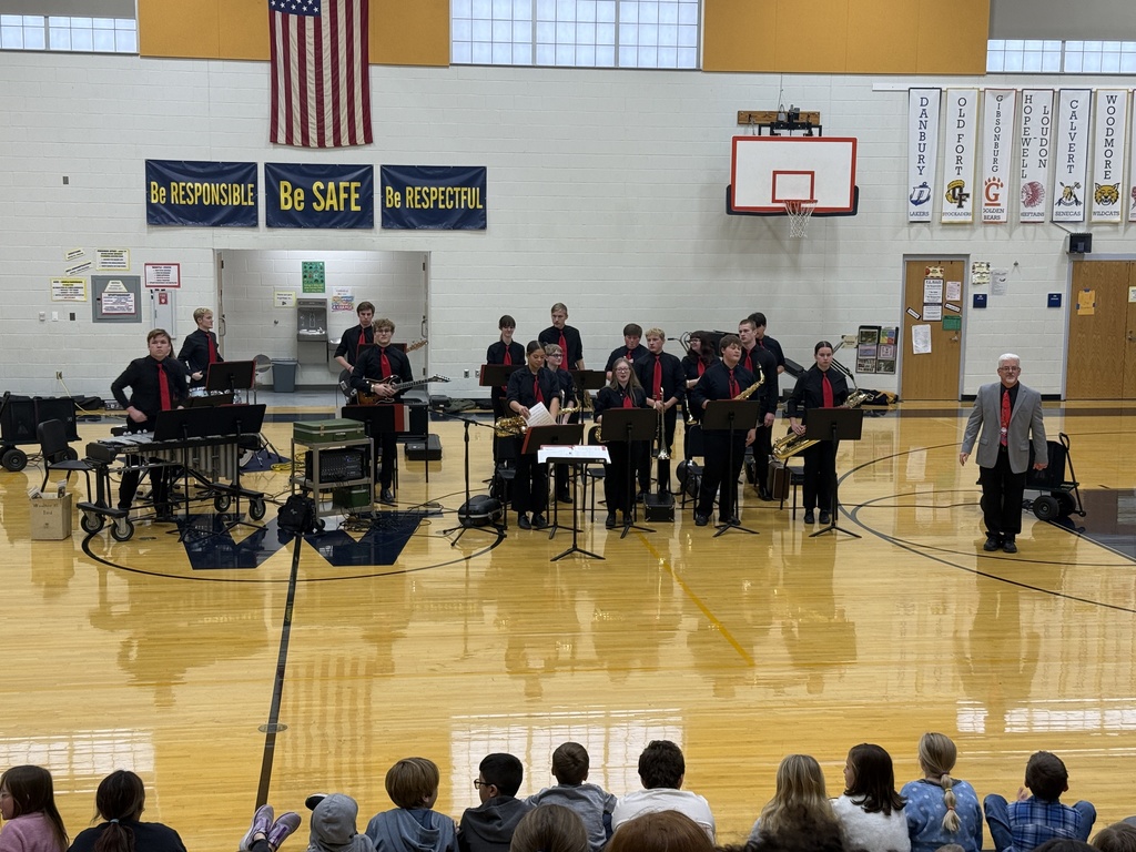 Our jazz band performs in the elementary/middle school gym. They are dressed in all black with red neck ties. Mr. Emerine, our band conductor, stands in front and all students are standing for their final bow.