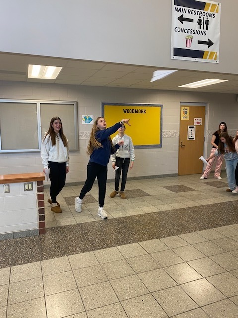 7th grade students test their paper airplanes in the cafetorium to see how far they can go! (Students are standing and throwing their paper airplanes)