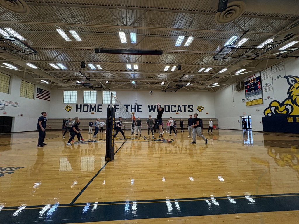 Students compete in a volleyball game in the gym.