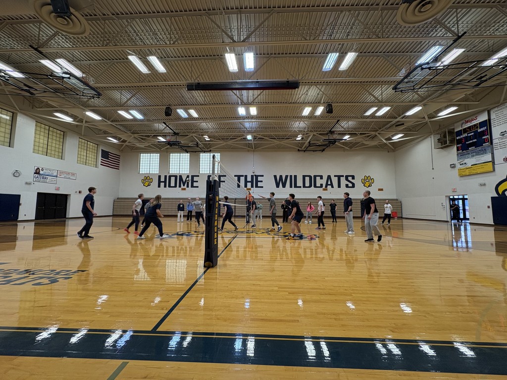 Students compete in a volleyball game in the gym.