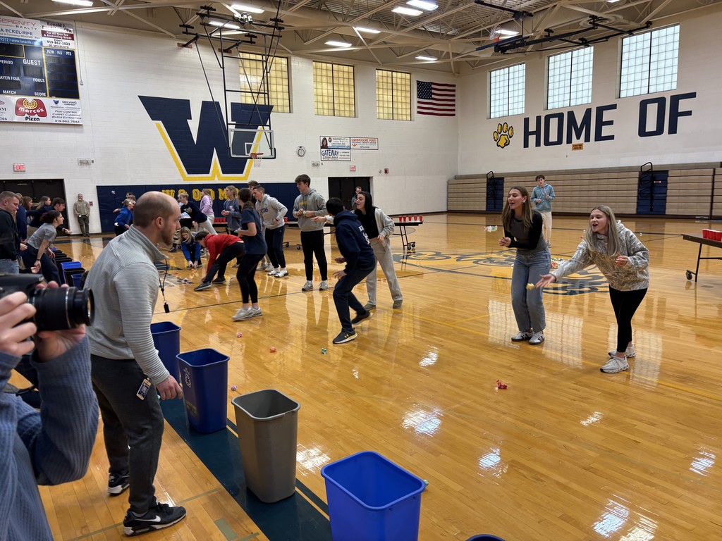 Another picture from a different angle of the tossing game. We can see a few students head on as they toss their objects into the cans.