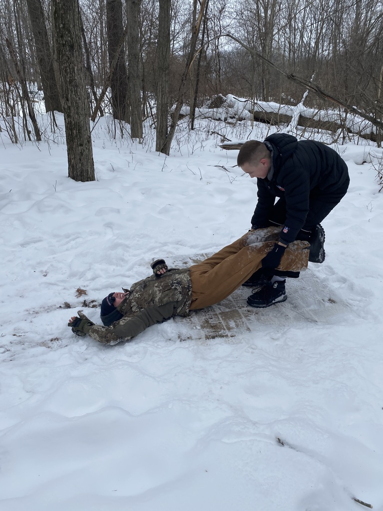 A sixth grade student pulls another student onto the platform during an outside team building activity in the snow.