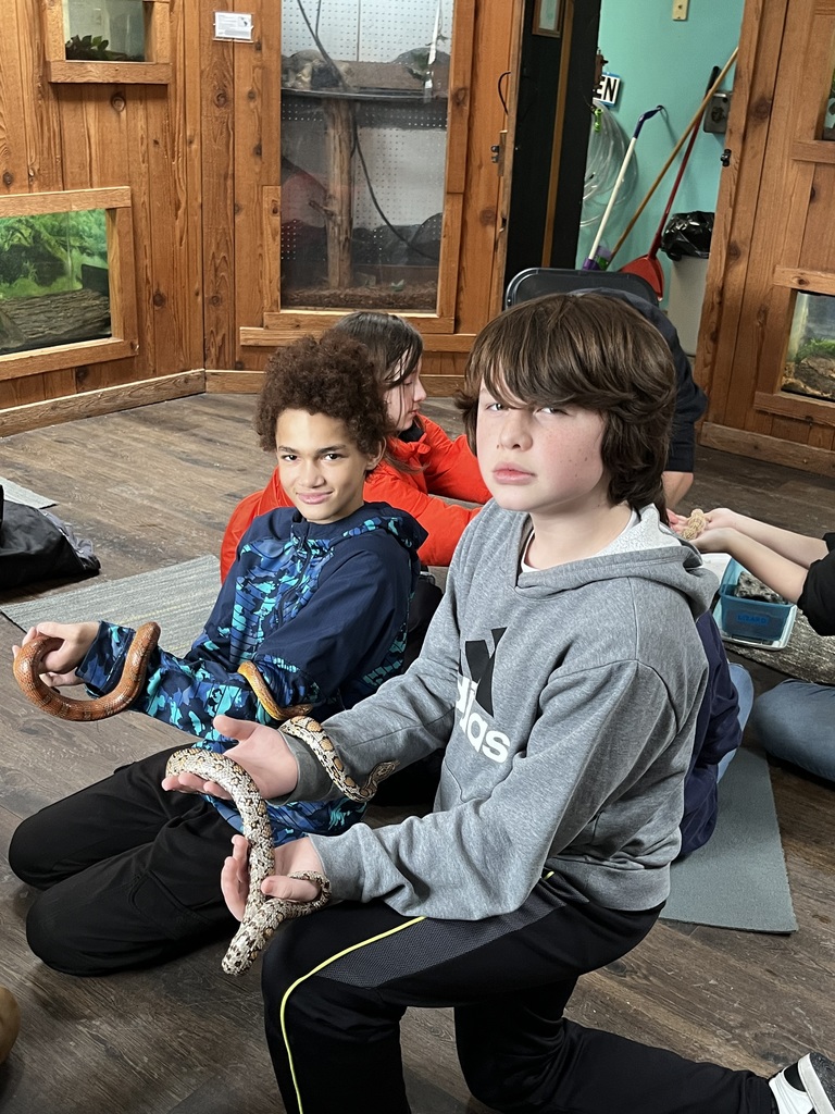 Two sixth grade boys hold snakes during one of the indoor lessons at camp.