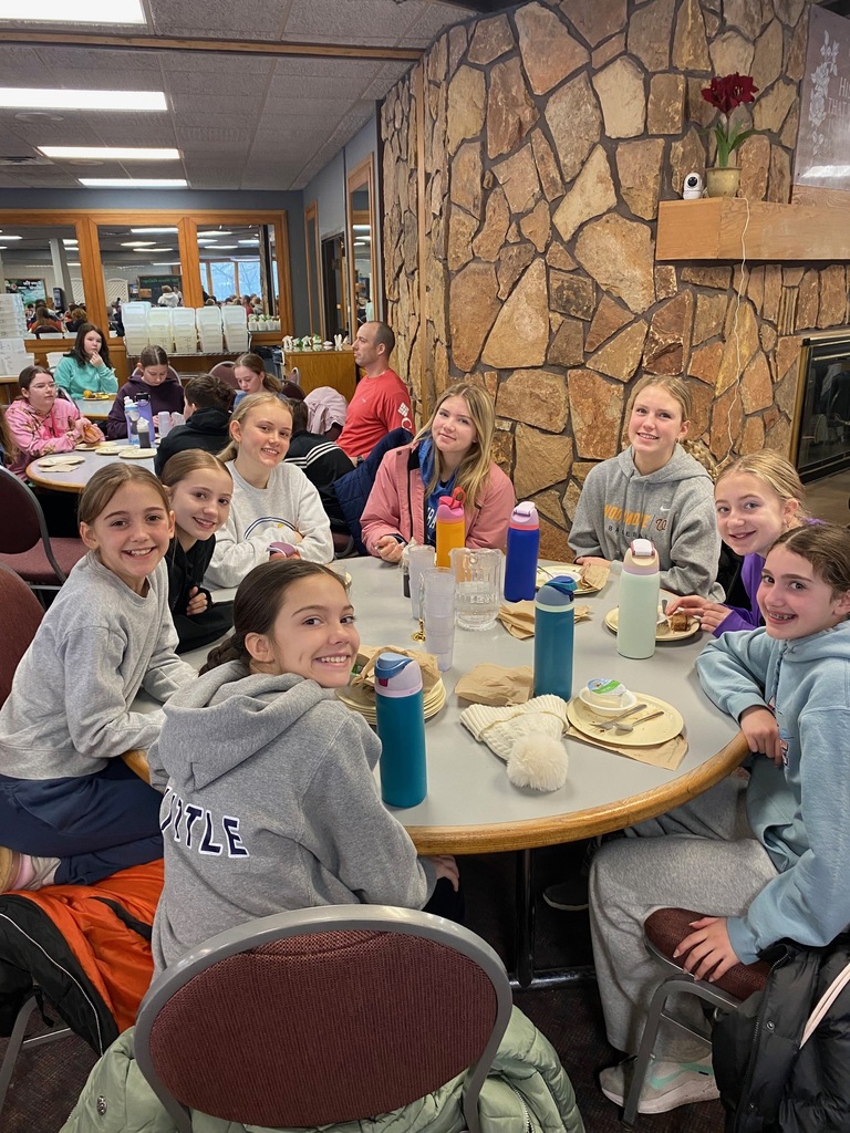 A table of sixth grader girls sitting around their table for a meal with their high school cabin leaders.
