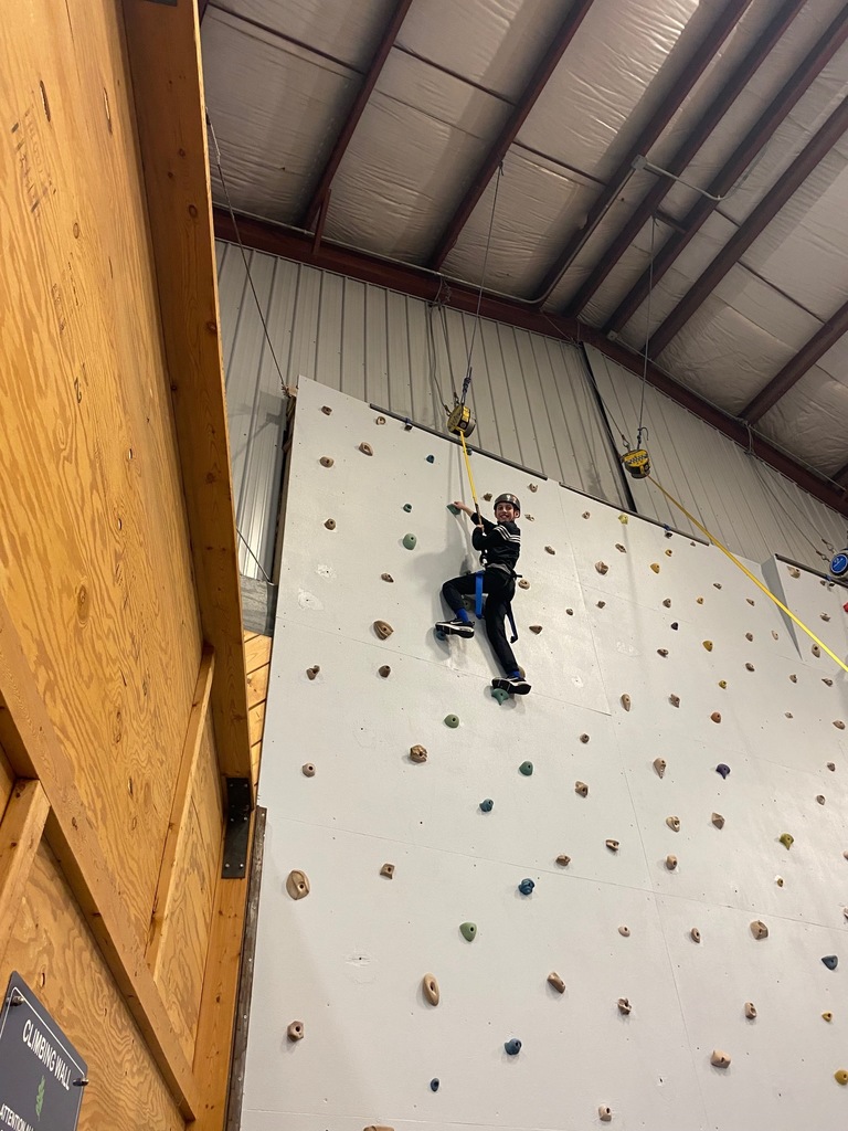 A sixth grade student scales the climbing wall and has almost reached the top!