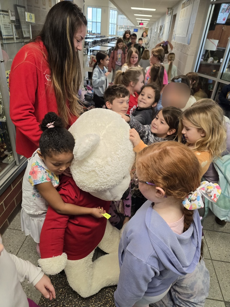 Elementary students crowd around a giant stuffed white bear during the Friday Dance Party in the main lobby area of the Pre-K through 8 building.