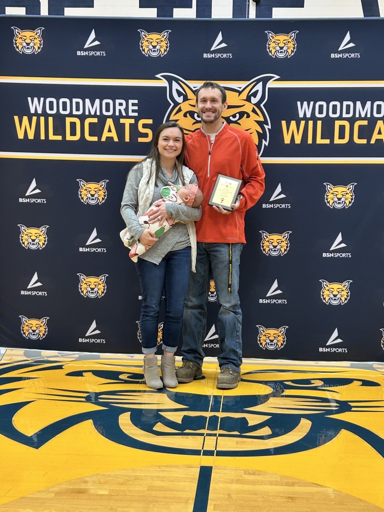 Mr. Avers stands with his wife and child in front of the Woodmore backdrop.