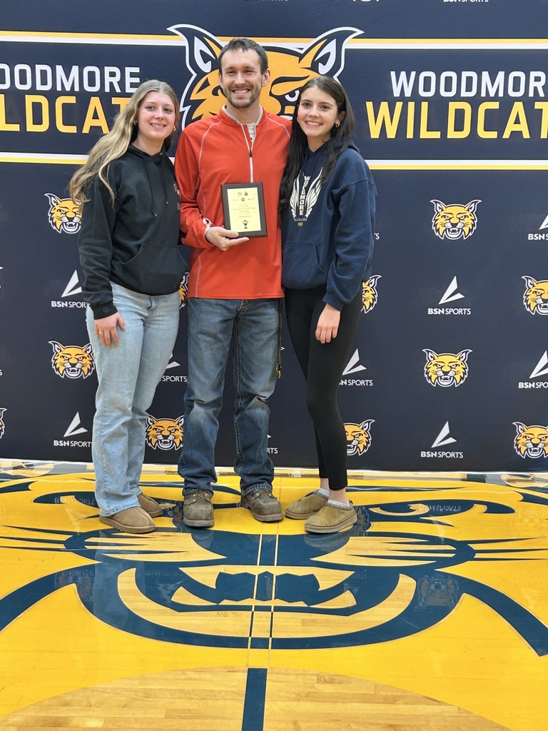 Mr. Avers stands in front of the Woodmore backdrop with the two students who nominated him.