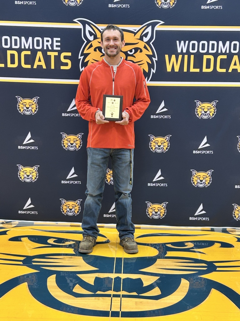 Mr. Avers poses with his plaque recognizing him as a top 10 Agricultural educator in Ohio! The Woodmore backdrop is behind him. (blue with Woodmore Wildcat heads all over it and the BSN Sports logo in white. 