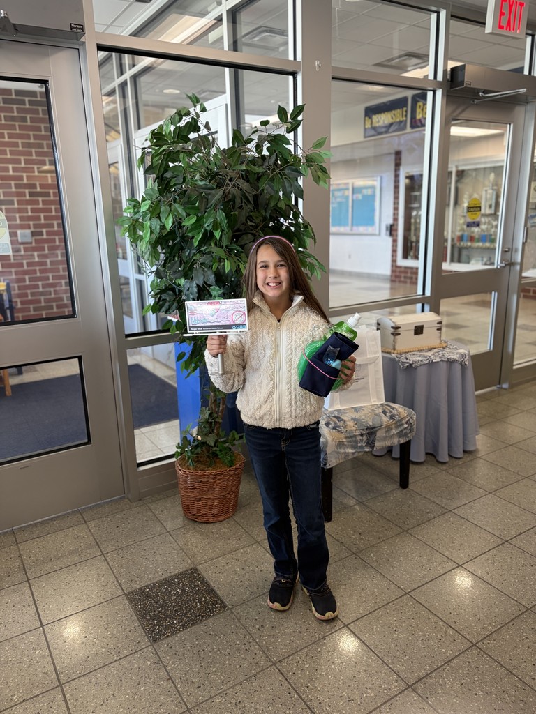 Harper posing in the main office with her billboard and additional gifts.