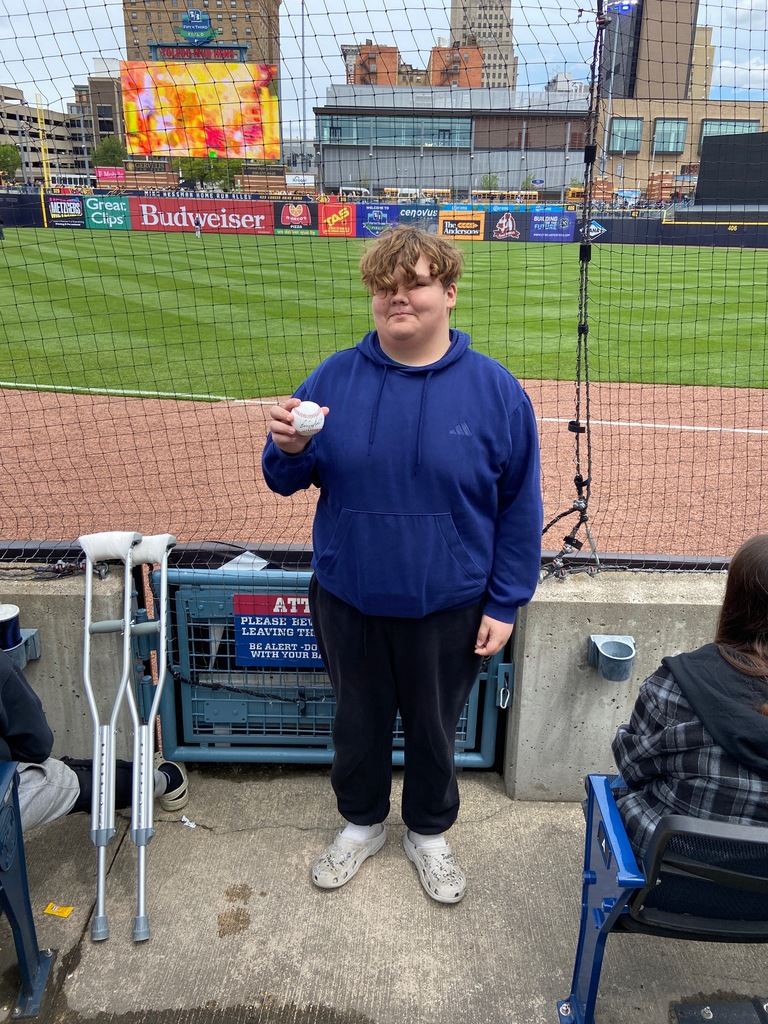 Paxton posing in front of the netting at the ball park with his signed ball from throwing out the first pitch.