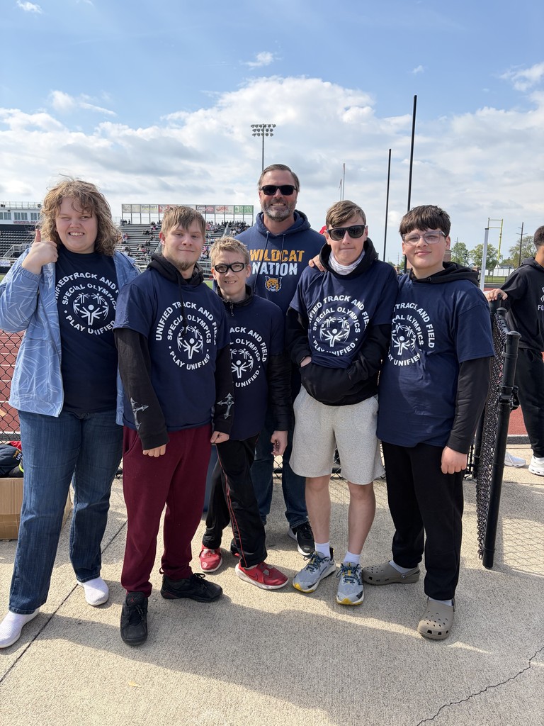 Mr. McCarthy with his students posing for a picture on the track at Perkins High School. All of the students are wearing blue Special Olympics shirts.