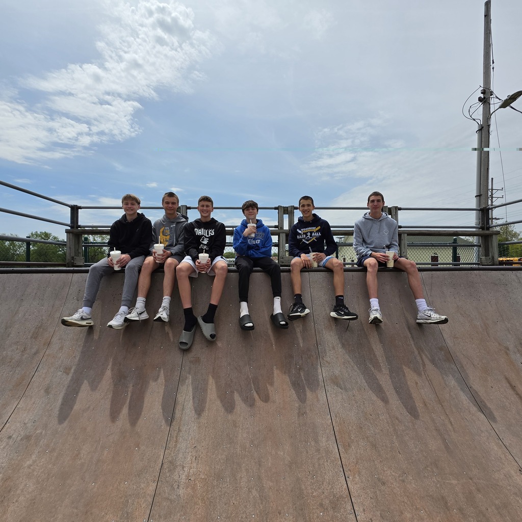 A group of students is sitting on the top of the half-pipe drop in at the park in Genoa.