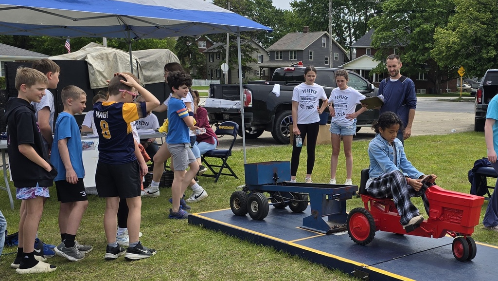 A group of students waits in line as a student sits on the tractor and does the mini tractor pull. 