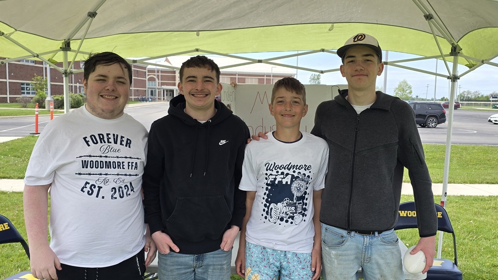 Four students stand in front of their Meat Production display board, smiling for the camera.